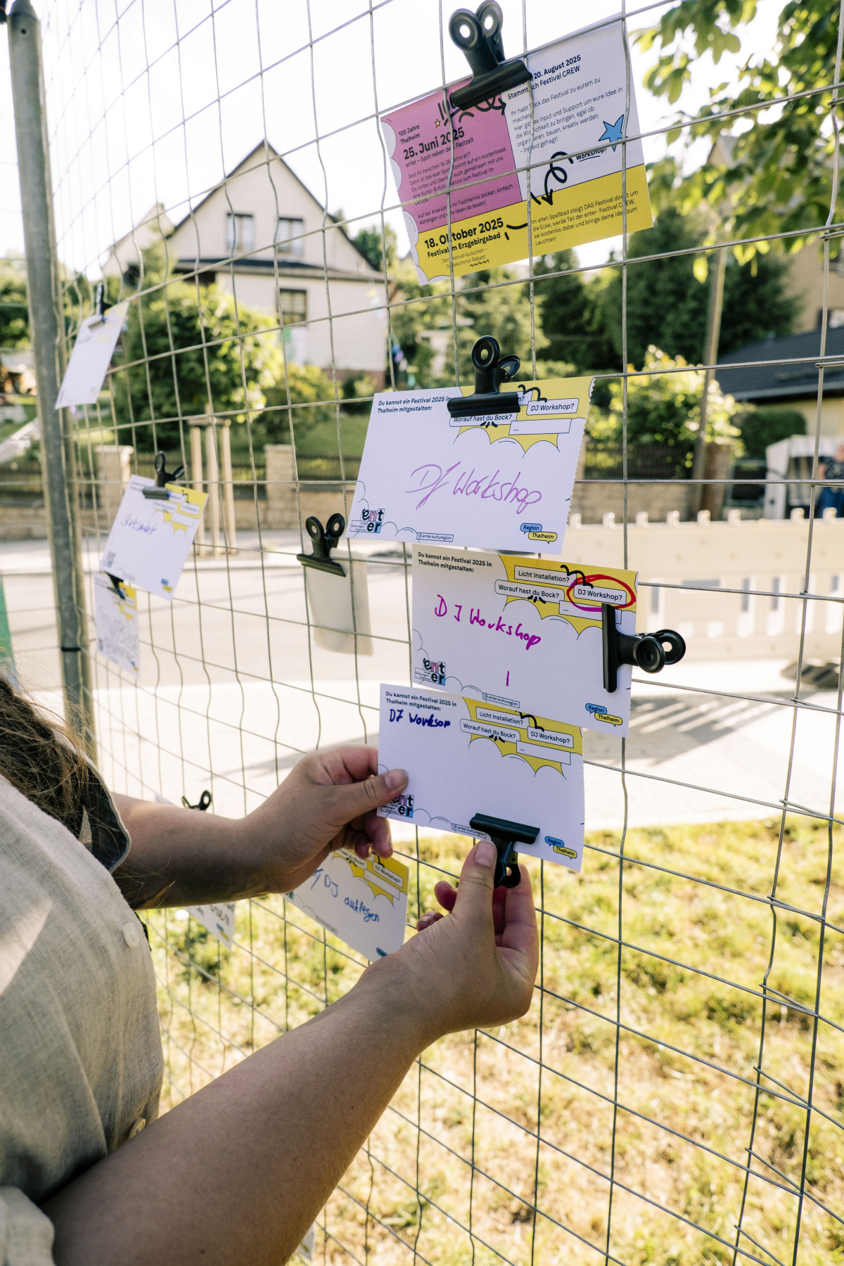 Helena hängt ausgefüllte Zettel an ein Gitter