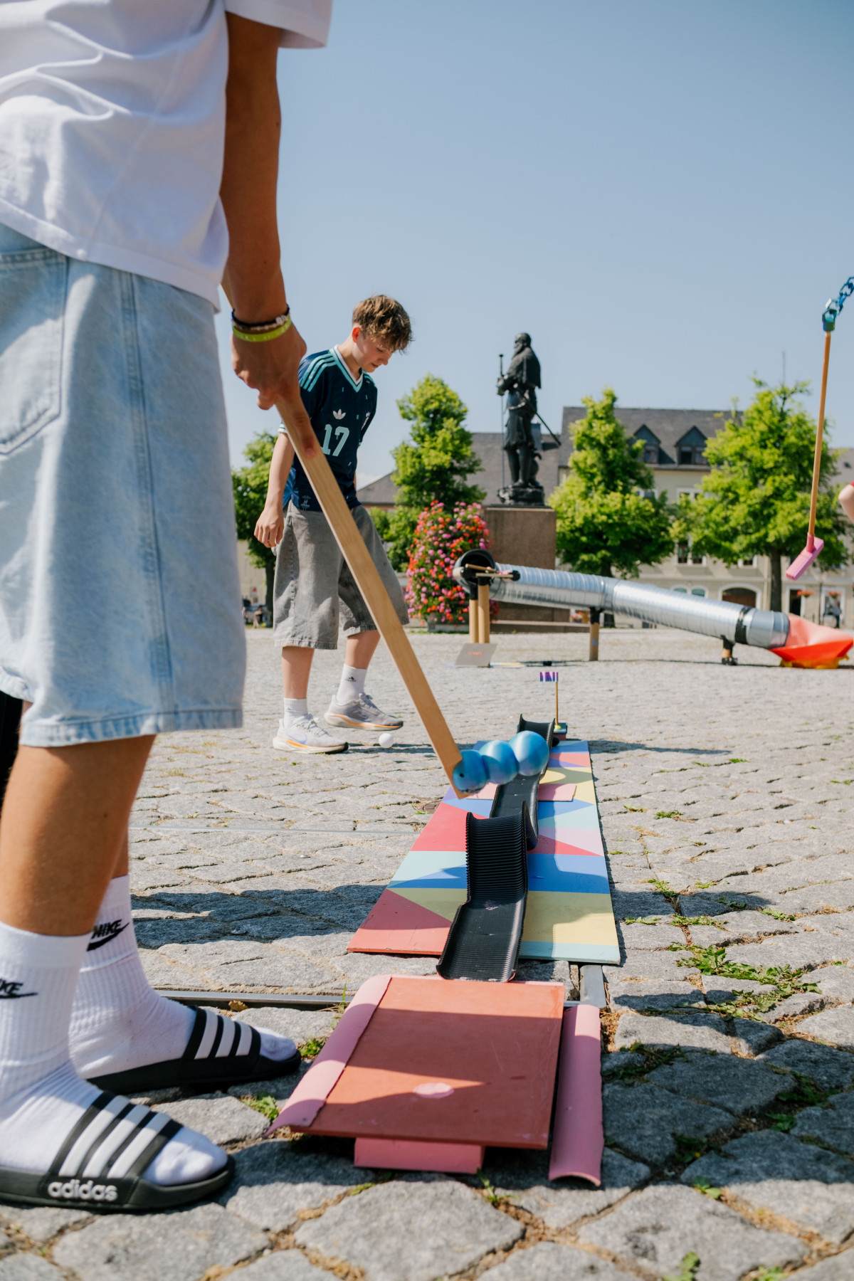 Junge spielt Minigolf im hintergund Statue