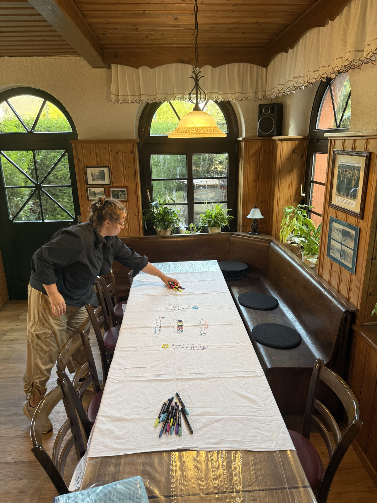 Person an einem Tisch mit Tischdecke und Stiften zum draufschreiben